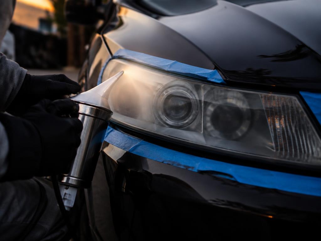 Applying a heat-cured vapor sealant to a taped-off headlight lens
